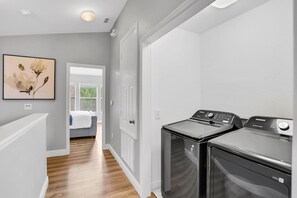 A laundry room with two washing machines and a dryer, a door leading to another room, and a framed artwork on the wall. - 3bd/3ba Windsor Hills, 10 min to Disney (Kissimmee)