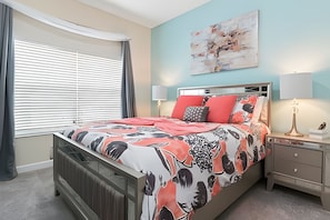 A bedroom with a bed, bedside lamps, a radiator, a nightstand, and a window with blinds. - Storey Lake 4BR Townhome 10min to Disney (Kissimmee)