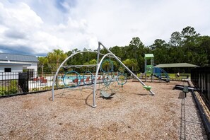 A playground with a swing set, climbing structures, and a slide. - Storey Lake 4BR Townhome 10min to Disney (Kissimmee)