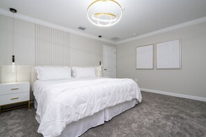 A bedroom with a large bed, a bedside table, a nightstand, a ceiling light fixture, and two framed pictures on the wall. - 4BR Storey Lake Townhome, Private Pool (Kissimmee)