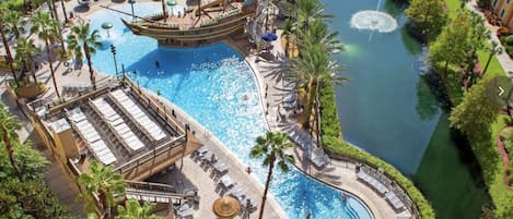 A resort with a large central pool, a ship-shaped water slide, and multiple sunbathing areas.