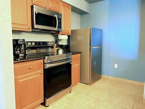 A kitchen with wooden cabinets, a stainless steel microwave, a gas stove, an oven, and a refrigerator. - Lake Buena Vista Resort - 2BR Condo (Orlando)