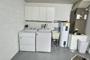 Une buanderie équipée d’un lave-linge et d’un sèche-linge, d’un petit évier et d’un réfrigérateur.
