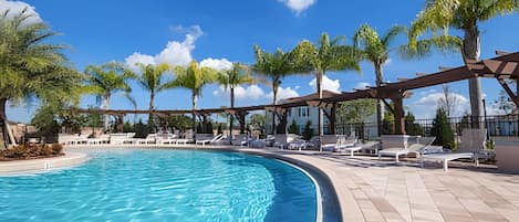 A swimming pool with lounge chairs and palm trees.
