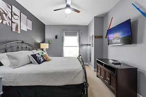 Ein modernes Schlafzimmer mit einem Bett, einem Fernseher und einem Schreibtisch.