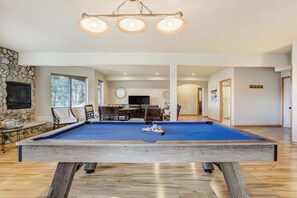 A pool table in a spacious living area with a stone fireplace, a television, and a dining area. - Timberline Hideout! Secluded Mtn Escape w Hot Tub (Woodland Park)
