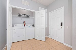 A laundry room with a washer and dryer, a fire extinguisher, and a door. - Vista Cay 3BR Condo w/ Balcony & Heated Pool (Orlando)