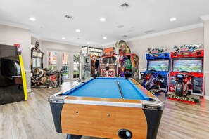 Een pooltafel in een ruimte met spelautomaten en een standbeeld.
