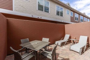 Eine Terrasse mit Tisch und Stühlen, ein überdachter Bereich und ein Gebäude im Hintergrund.