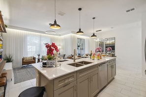 A modern kitchen with a central island, pendant lighting, and a large window. - 4BR Storey Lake Townhome, Heated Pool (Kissimmee)