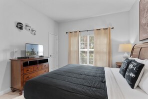 A bedroom with a bed, a dresser, a television, and a window with curtains. - Storey Lake 4BR Townhome - 10 min to Disney (Kissimmee)