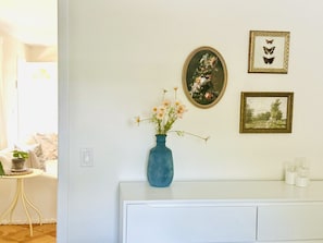 A room with a white dresser, a blue vase with flowers, and three framed pictures on the wall. - Pixie and Orchard Cottages - Sleeps 7 (Ojai)