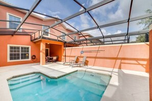 A swimming pool with a glass ceiling, outdoor seating, and a view of a house in the background. - 4BR Townhome w/ Private Pool at Paradise Palms (Kissimmee)
