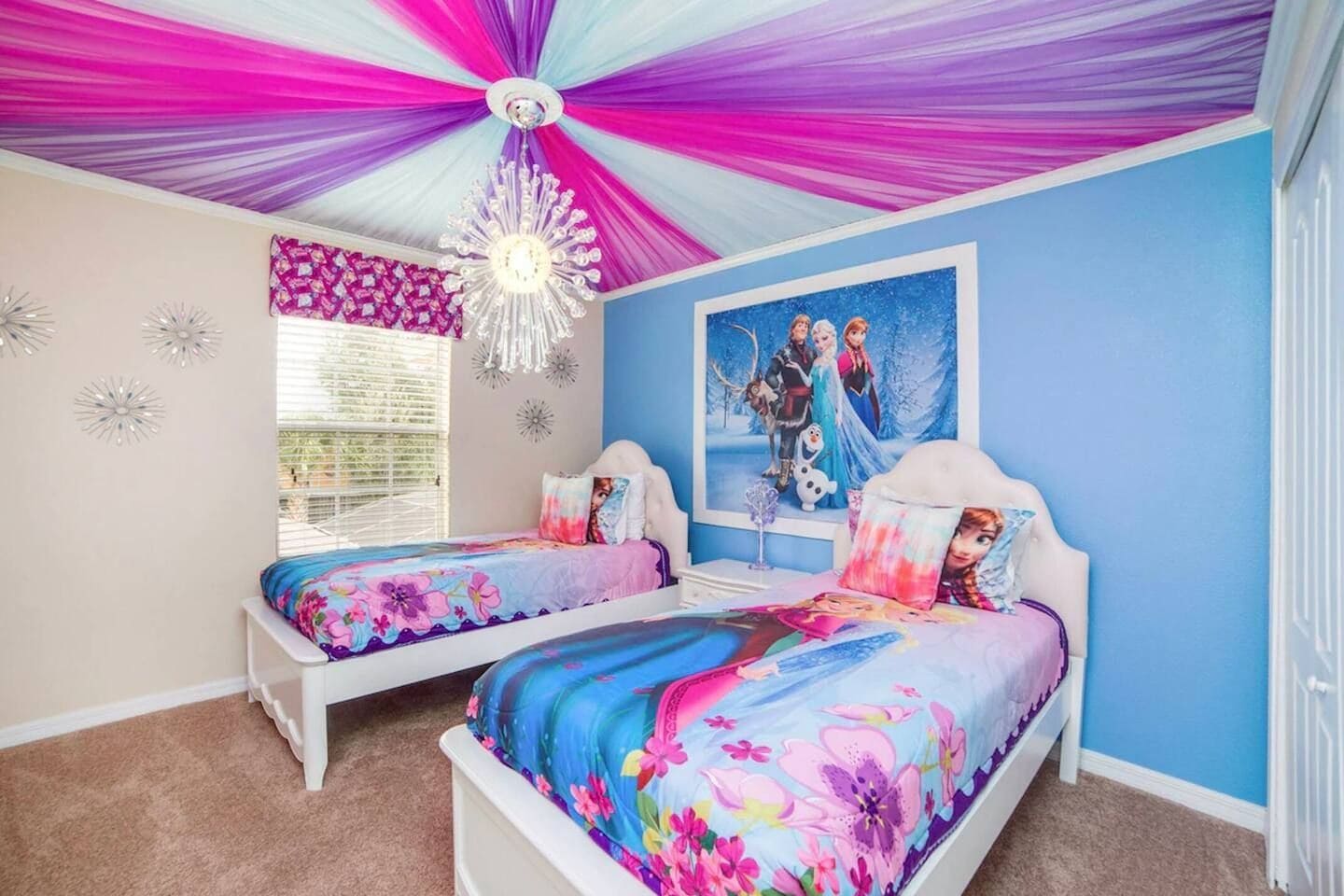 Een slaapkamer met twee bedden, een plafondventilator, een raam met zonwering en een aan de muur hangend schilderij.