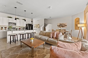 A modern kitchen with white cabinets, a central island with stools, and pendant lighting.