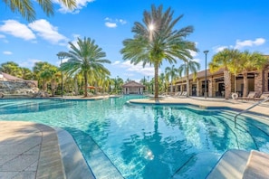 A swimming pool with palm trees, a stone building, and a clear blue sky. - Themed 4BR Home w/ Pool at Solterra Resort (Davenport)