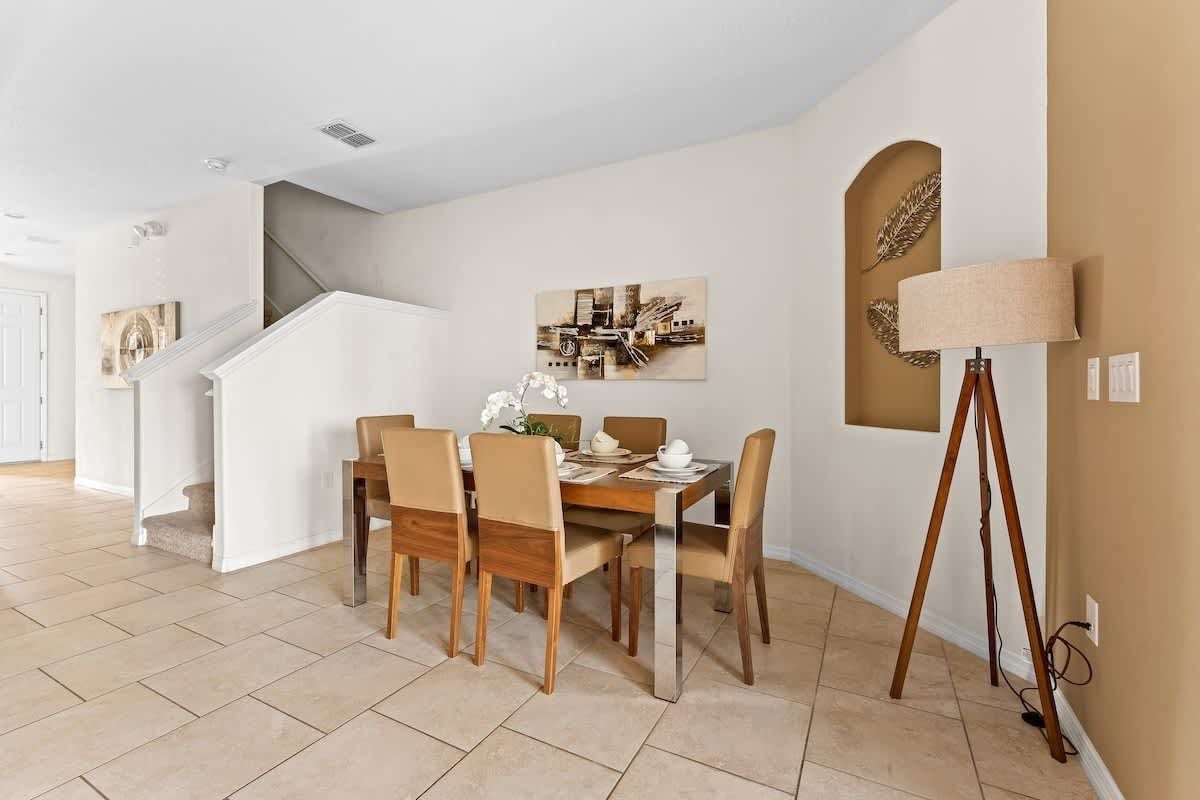 Un comedor con una mesa y sillas de madera, una lámpara y un cuadro en la pared.