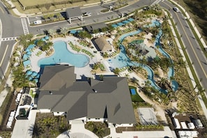 Um resort com uma grande piscina, áreas de estar e uma estrada ao fundo.