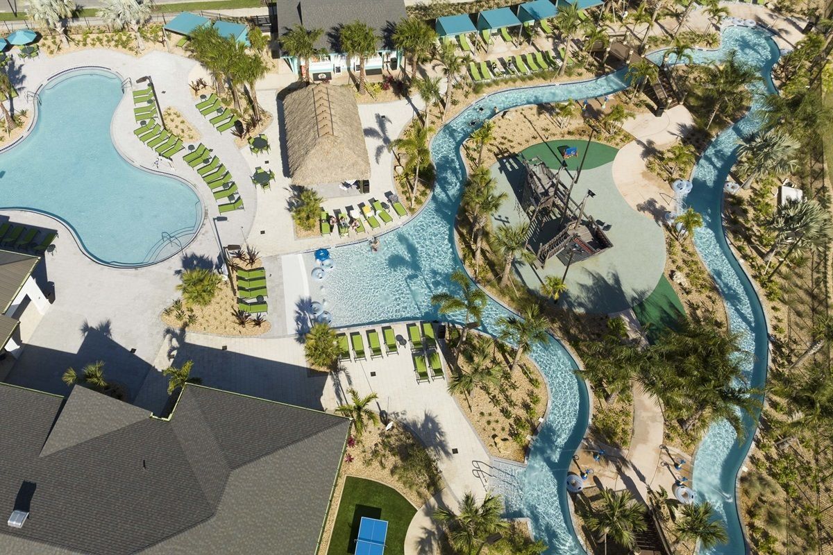 An aerial view of a resort with a large swimming pool, a water slide, and multiple lounge areas.