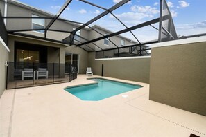 An indoor swimming pool with a glass enclosure, a covered patio area, and a view of the sky. - 4BR Storey Lake Townhome, Heated Pool (Kissimmee)