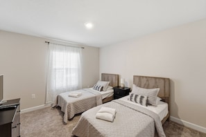 A hotel room with two single beds, a desk, and a television. - Championsgate Pool Home Near Disney Parks (Davenport)
