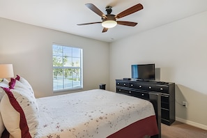 A bedroom with a bed, a dresser, a television, and a ceiling fan. - 4BR Paradise Palms Home With Pool (Kissimmee)
