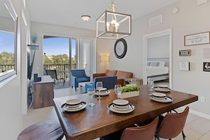 Un comedor con una mesa de madera dispuesta para cuatro, una silla azul y vistas al exterior.