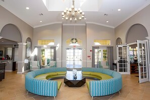 A spacious lobby with a central seating area, high ceilings, and a chandelier. - Vista Cay 3BR Townhome Near Universal & Occc (Orlando)