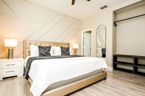 Een moderne slaapkamer met een groot bed, nachtkastjes, een spiegel en een kledingkast.