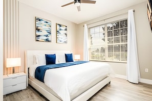 A bedroom with a bed, nightstands, a ceiling fan, and a window with blinds. - Windsor Hills Luxe 4BR Villa w/ Pool & Game Room (Kissimmee)
