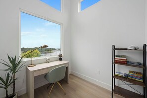 A room with a desk, chair, bookshelf, and a window with a view of a landscape. - Modern Waterfront Escape on Lake Buchanan (Buchanan Dam)