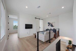 Ein modernes Wohnzimmer mit einer Couch, einem Flachbildfernseher und einer Treppe mit Geländer.