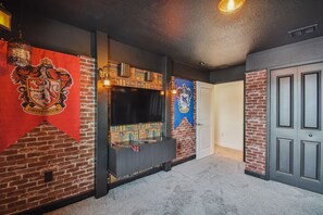 A hallway with a brick wall, a flat-screen TV mounted on a dark wooden console, and a door with a brick accent. - 4BR Storey Lake Home, Private Pool (Kissimmee)