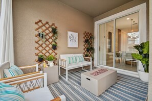 A modern outdoor seating area with a white sofa, striped cushions, and a coffee table. - 4BR Storey Lake Home, Private Pool (Kissimmee)