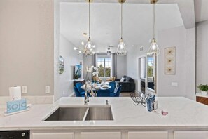 A modern kitchen with a large island, a double sink, and pendant lighting. - Modern 3BR Condo at Vista Cay Near Disney (Orlando)