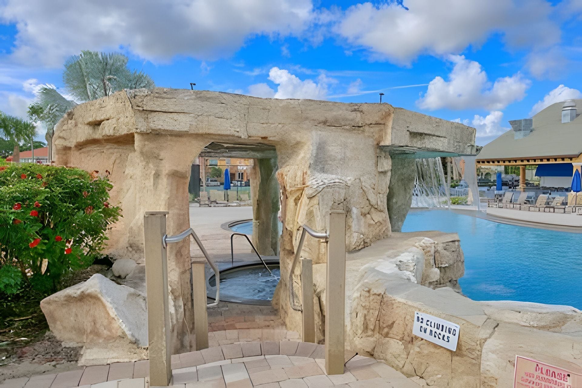 A stone archway leading to a pool area with a sign reading "Pool Area."