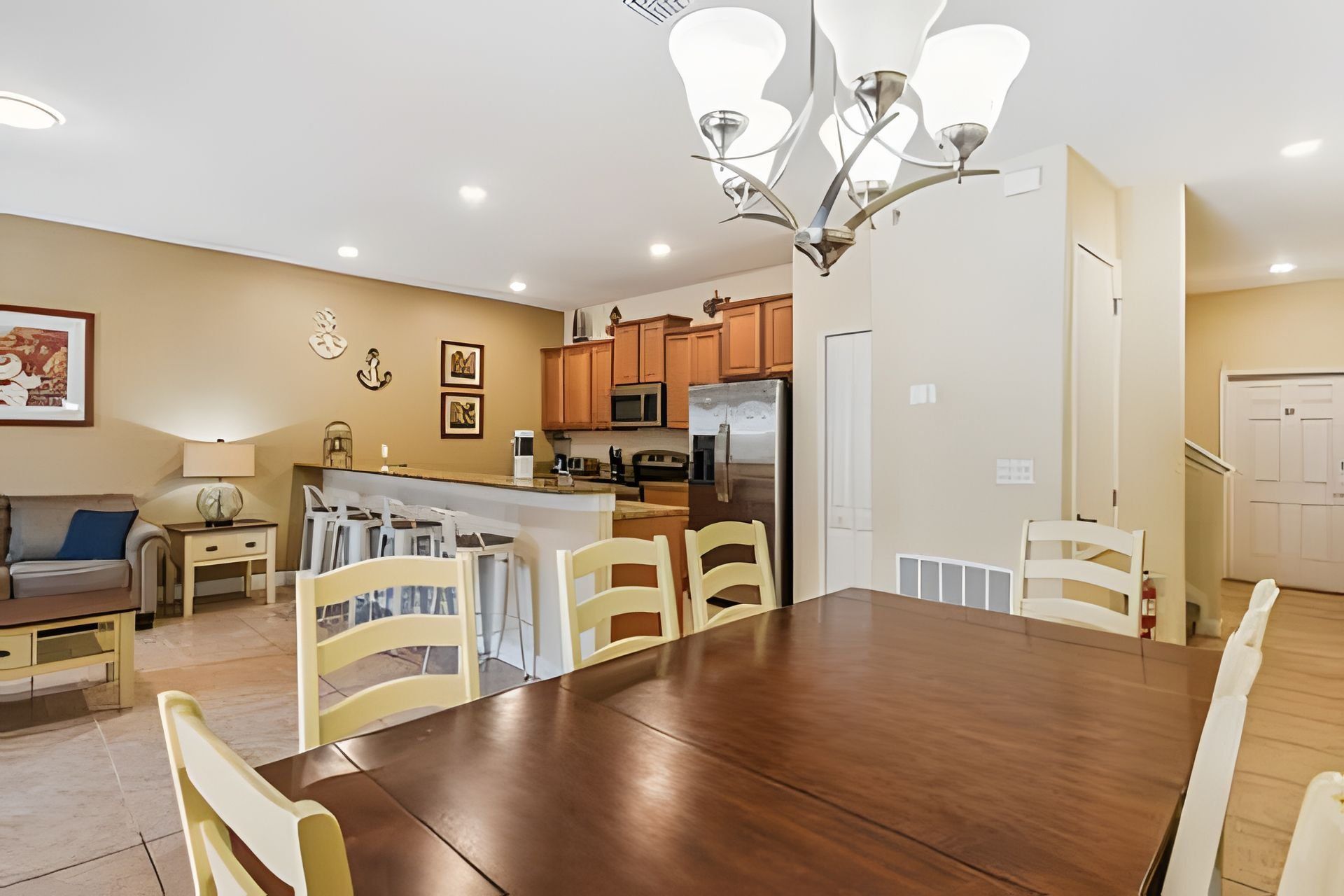 A modern kitchen with wooden cabinets, a stainless steel refrigerator, and a dining area with a wooden table and chairs.
