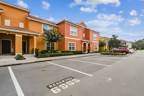 A row of modern townhouses with a reserved parking space marked on the street. - 4BR Paradise Palms Townhome With Pool (Kissimmee)