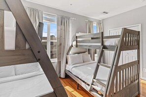 A room with bunk beds, a window with curtains, and a door. - 3-bedroom Condo at Vista Cay Near Disney (Orlando)