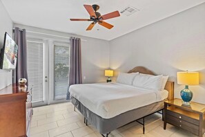 A hotel room with a bed, bedside tables, a ceiling fan, a TV, and a window with blinds. - 3-bedroom Condo at Vista Cay Near Disney (Orlando)