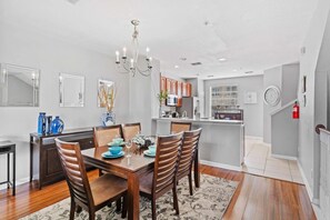 A modern kitchen with a central island, wooden chairs, and a chandelier. - 3-bedroom Condo at Vista Cay Near Disney (Orlando)