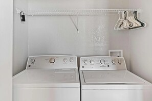 A laundry area with two front-loading washing machines and a drying rack with hangers. - 3-bedroom Condo at Vista Cay Near Disney (Orlando)