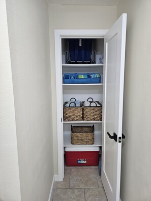 Ein Stauraum mit Regalen, Körben, gefalteten Decken und einer roten Aufbewahrungsbox.