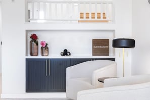 A modern living room with a white sofa, a dark blue cabinet, and a black floor lamp. - Sunset View Updated Villa Heated Pool  Kings (Waikoloa Village)