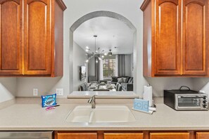 A kitchen with wooden cabinets, a double sink, a toaster, and a bag of Oreos. - Spacious 3BR Condo at Vista Cay Resort (Orlando)
