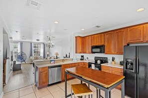 A modern kitchen with wooden cabinets, a stainless steel dishwasher, a black refrigerator, and a coffee maker. - Modern 3BR Townhome at Vista Cay Resort (Orlando)
