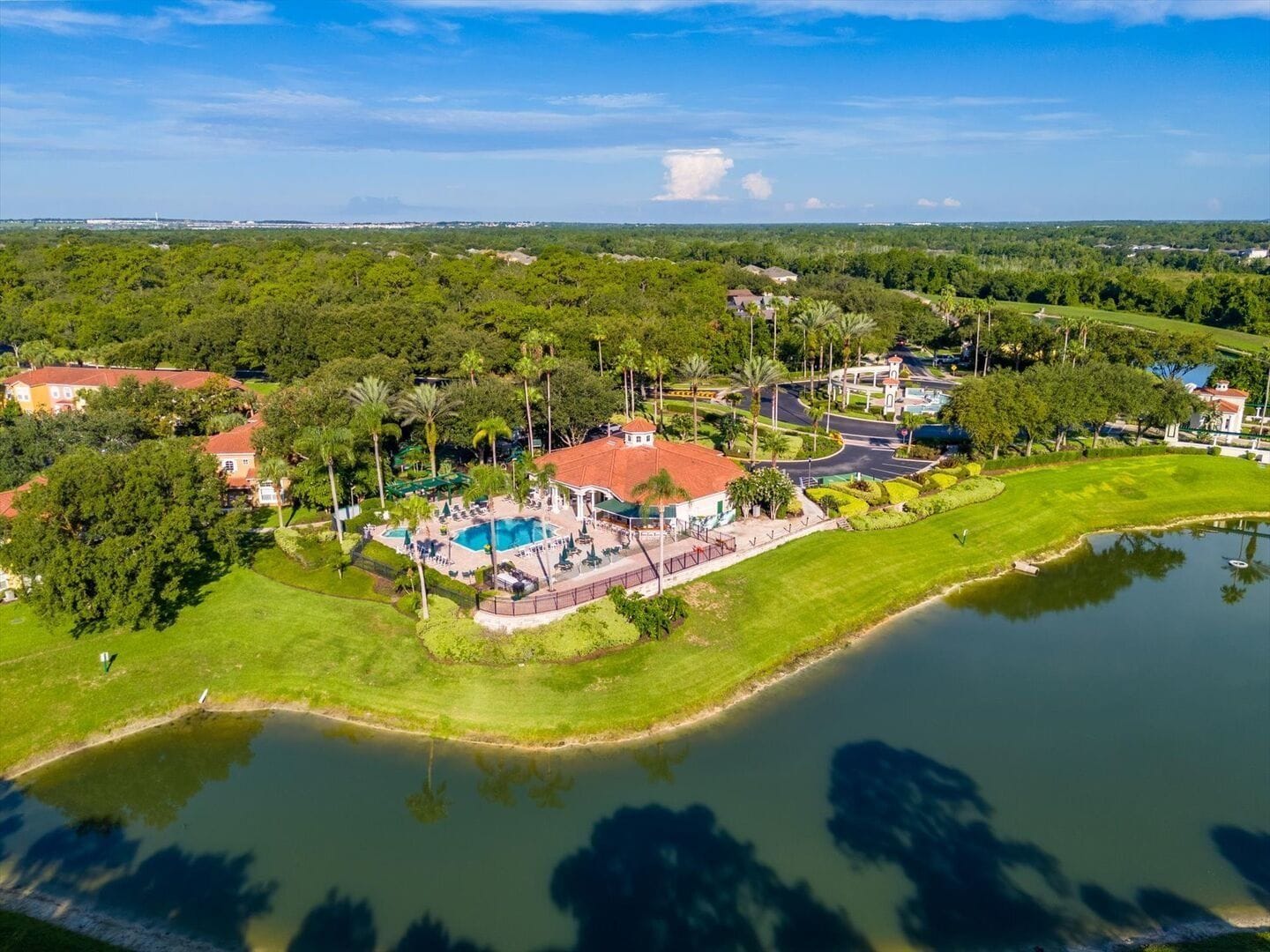 An aerial view of a resort with a swimming pool, a golf course, and a lake.