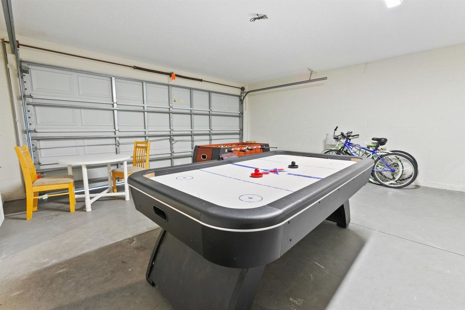 Un biliardo in un garage con una bicicletta e una sedia.
