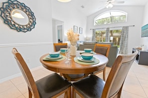 A dining area with a round wooden table set for four, surrounded by chairs. - 5BR Emerald Island Pool Home, Game Room (Kissimmee)