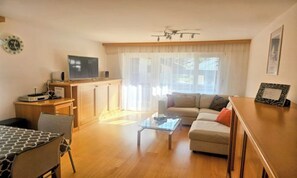 A living room with a sofa, coffee table, and a television on a stand. - PRIMAVISTA ZERMATT – PEACEFUL APARTMENT WITH MATTERHORN VIEWS (Zermatt)